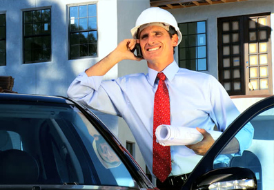 Photo of a talking on his cellphone while wearing a hard hat and a business suit