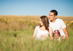 Photo of a happy family sitting in a grassy field posing for the camera