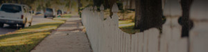 Photo of a sidewalk and white picket fence