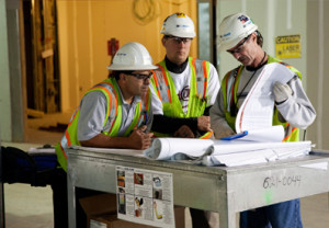 Photo of three men at work looking at a blueprint for a property