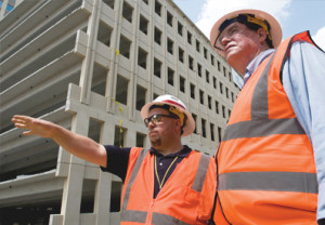 Photo of two men wearing orange vests and hard hats