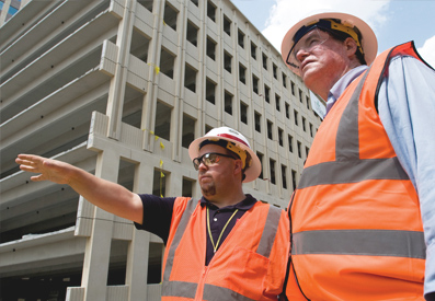 Photo of two men wearing orange vests and hard hats