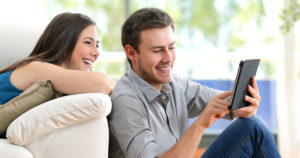 Photo of a man and woman laughing while looking at a cellphone