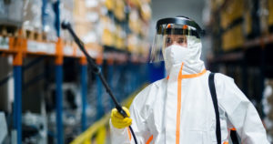 Man in hazmat gear spraying disinfectant chemicals