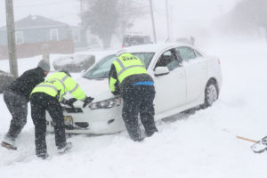 Photo of workers trying to get car out of the snow during a blizzard