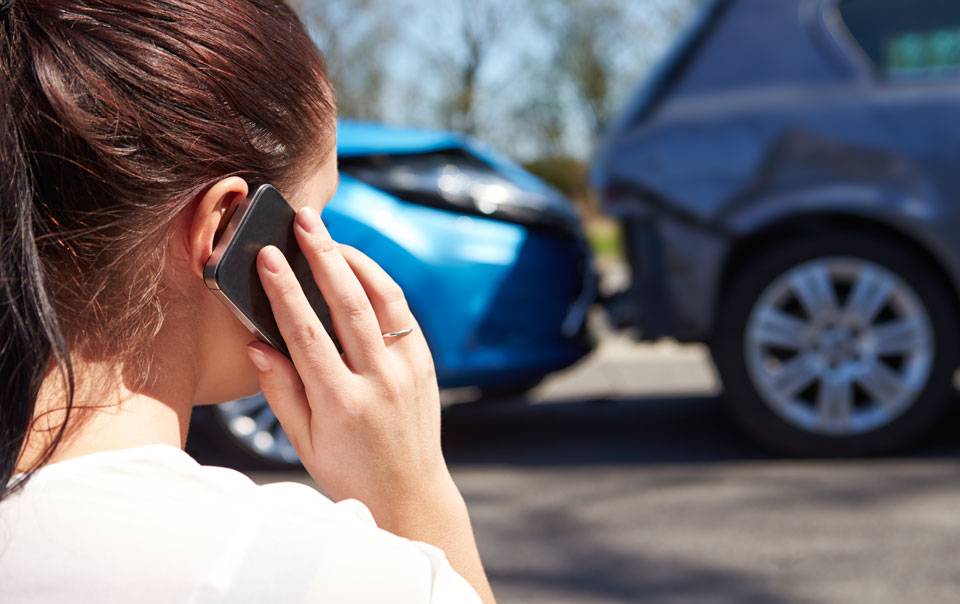 Photo of a woman on a cell phone reporting a car accident