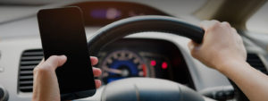 Photo of a man holding a cellphone while driving