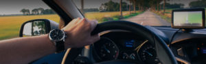 Photo of a driver holding the steering wheel while driving down a road